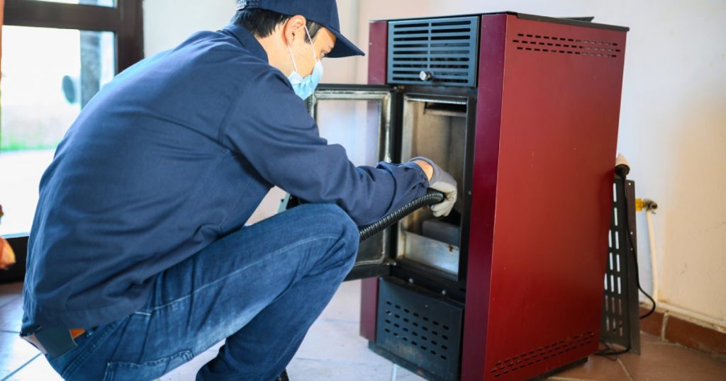 A pellet stove maintenance man works on a pellet stove